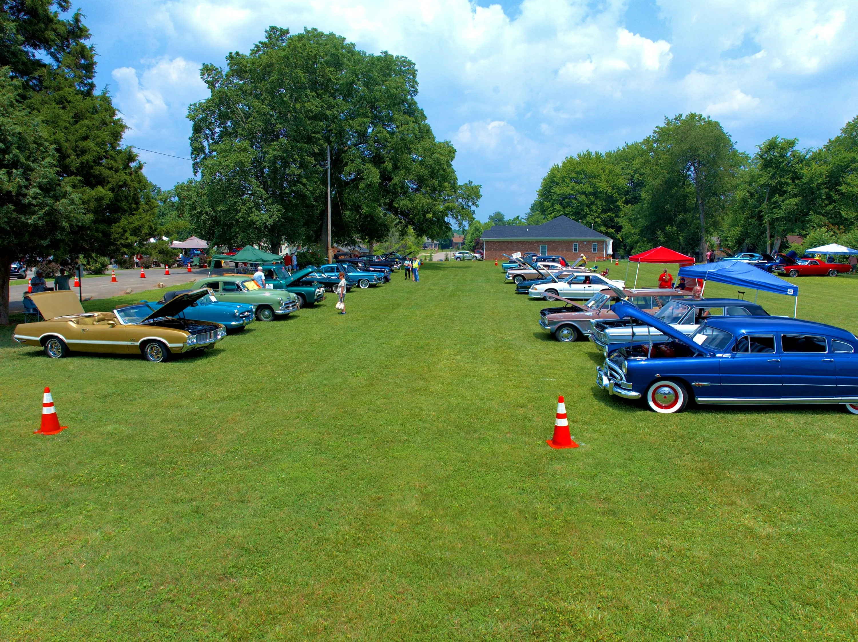 Show layout — a lower aerial reveals organized vehicle rows, vendor tents and attendee circulation.