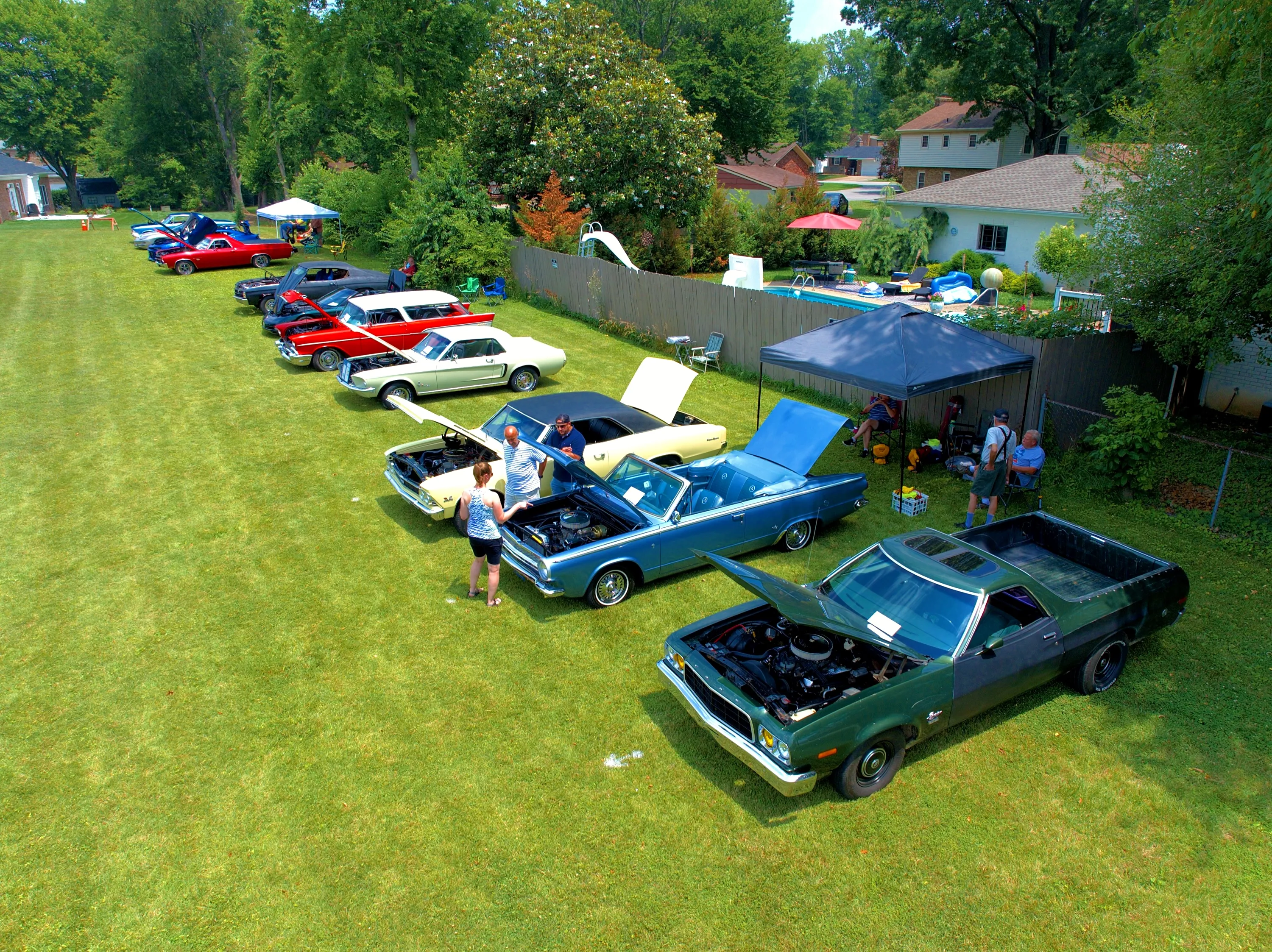 Attendee experience — close aerial coverage connects the featured vehicles with people exploring the show.