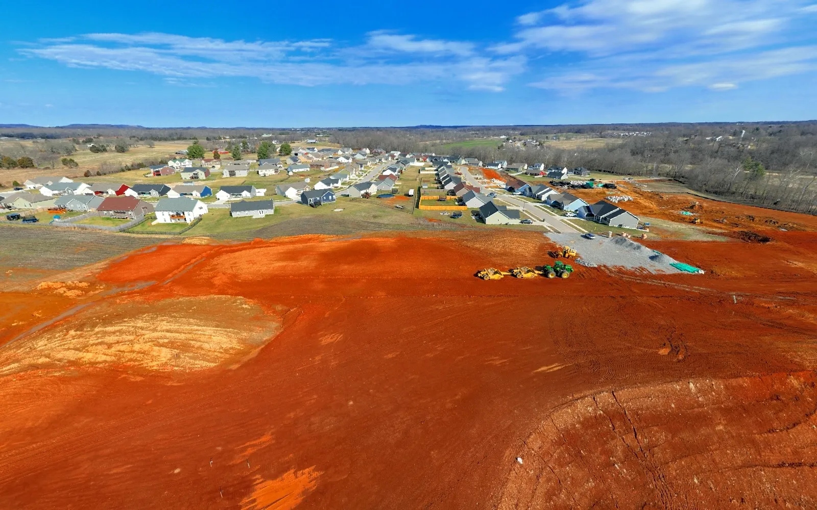 February 2024 — Mass grading expands across the next residential phase, with equipment and aggregate staged at the site entrance.