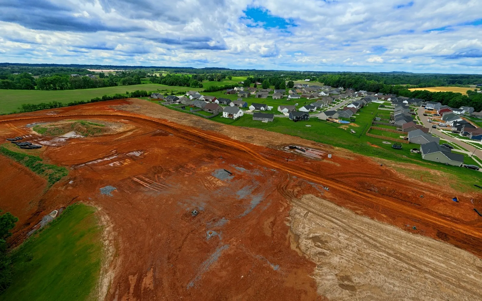 May 2024 — Rough road alignment, drainage and utility preparation become visible across the graded lots.