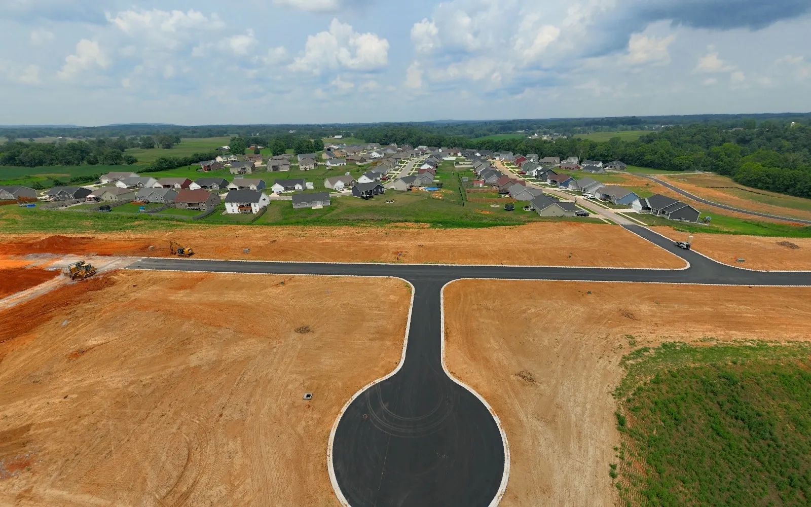 July 2024 — New streets, curbs and the first cul-de-sac establish the permanent circulation network.