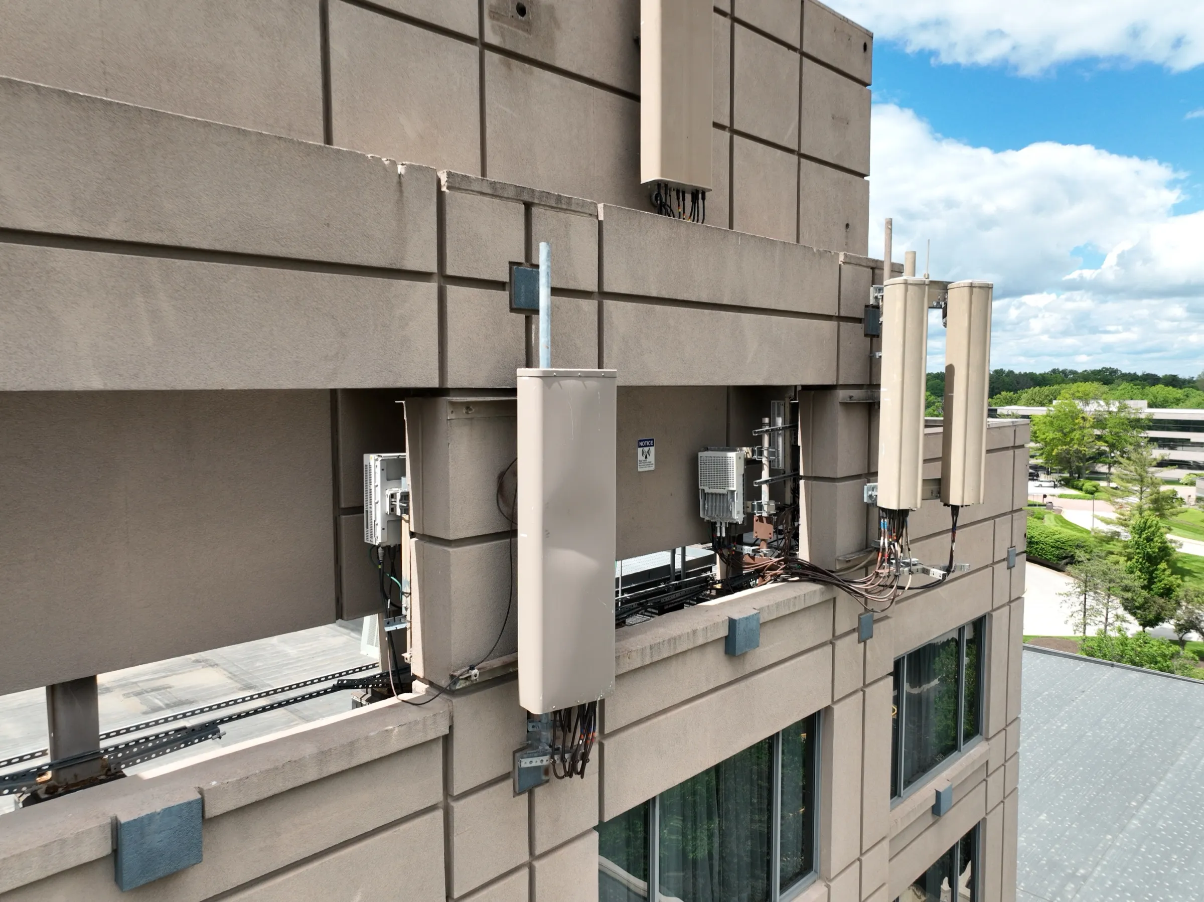 Close aerial inspection image of building-mounted telecom equipment